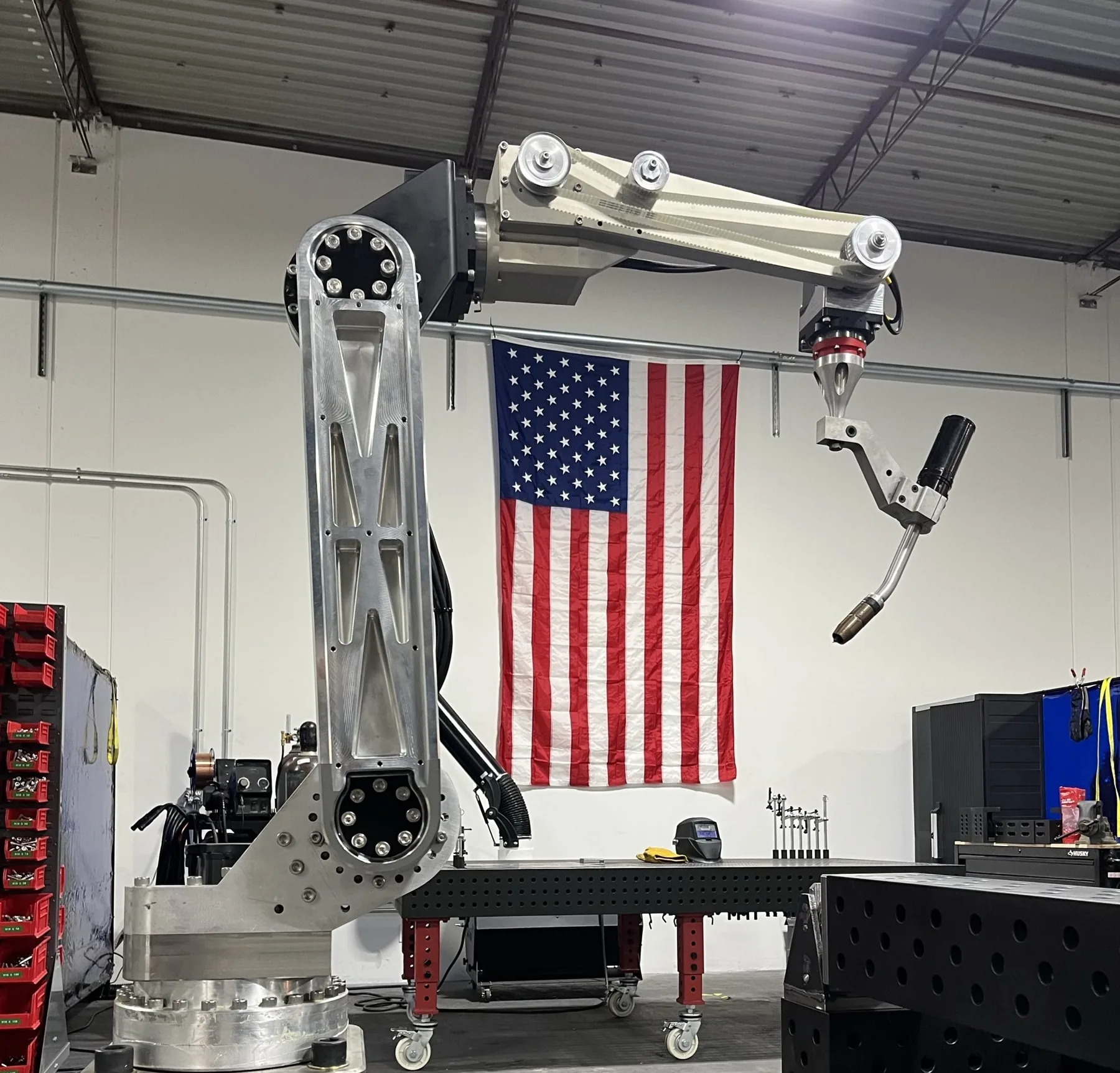 Rosie 1400 six-axis arm with a MIG torch beside a US flag